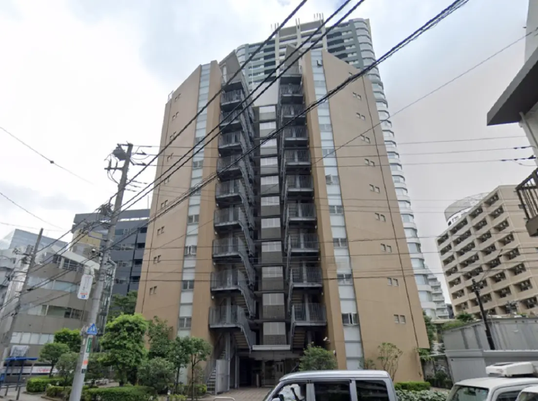 - モダンなデザインのマンションの外観、バルコニー付きの階段と周囲の緑豊かな景観、都市のビル群に囲まれた立地