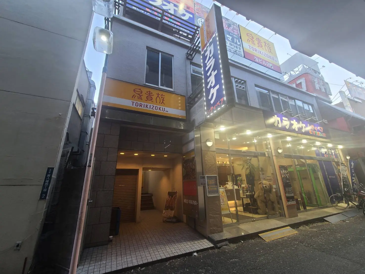 繁華街にある焼き鳥屋「鳥貴族」の店舗外観、看板と入口が明るく照らされている