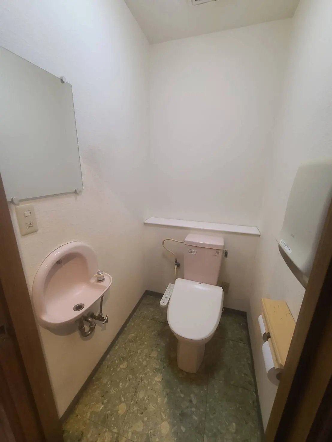 シンプルなデザインのトイレと洗面台、緑色のマーブルフローリングが特徴のバスルームインテリア