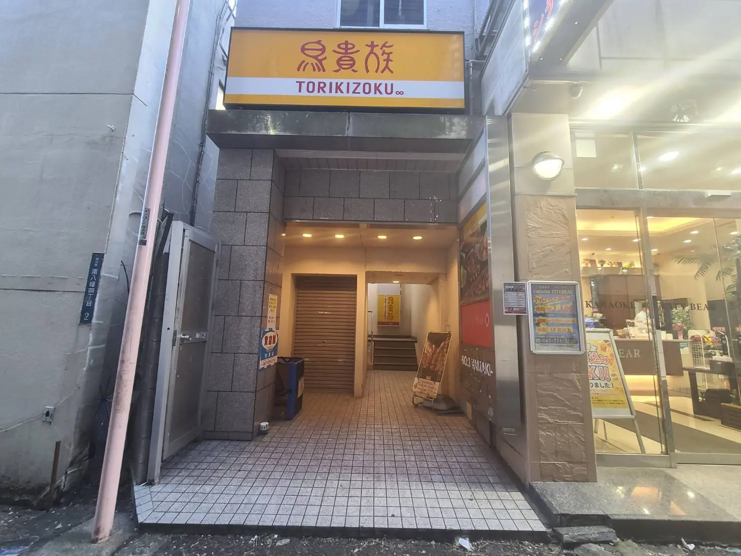 都会のビルの間にある鳥貴族の入口、夜間の街並みと照明