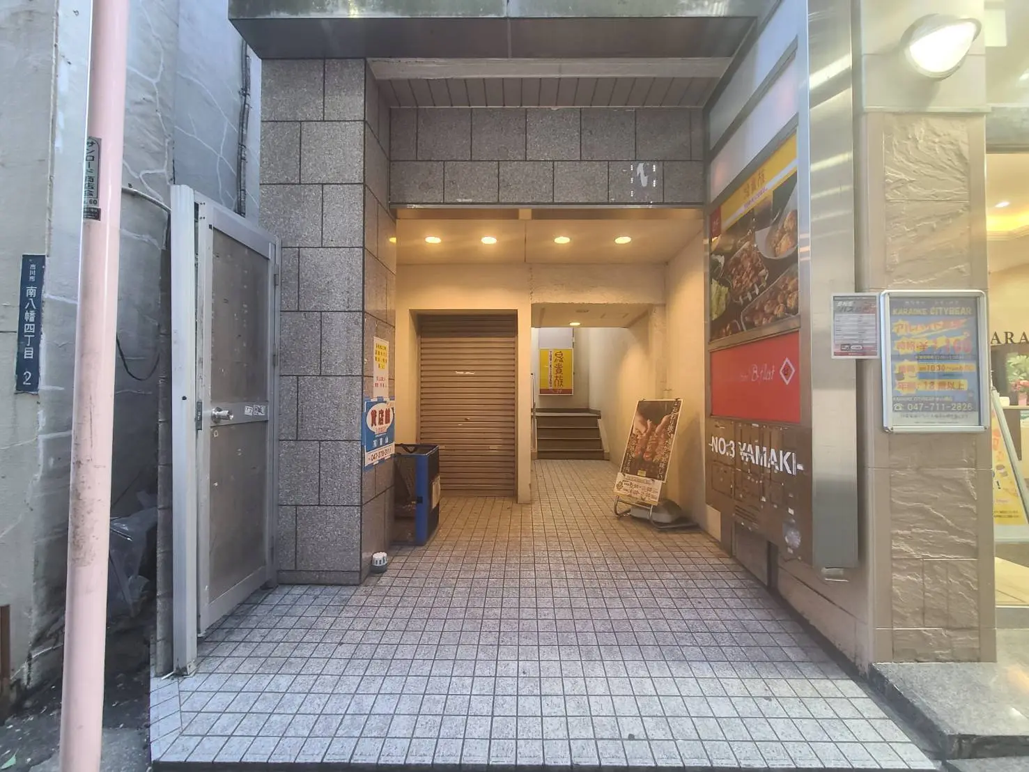 都会のビルの間にある狭い通路、周囲にレストランの看板やポスターが掲示されている街角の景色