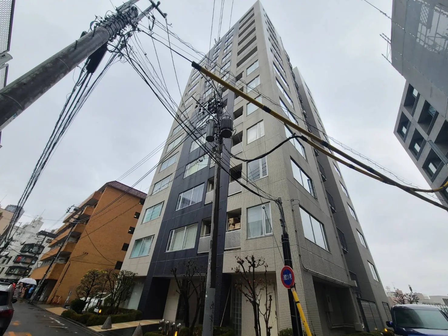 都市の景観、多くの電線が張り巡らされた電柱と近代的なマンションの外観