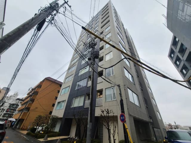 都市の景観、多くの電線が張り巡らされた電柱と近代的なマンションの外観