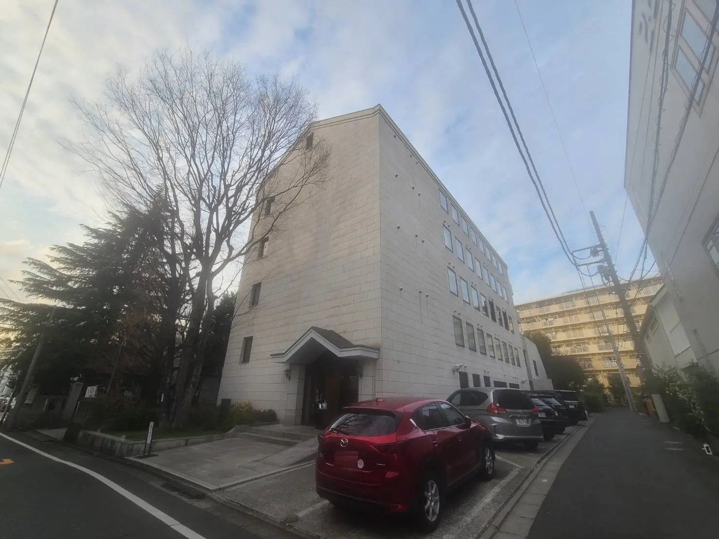 都市の建物の外観、駐車場に車がある風景、空が見える明るい日の午後