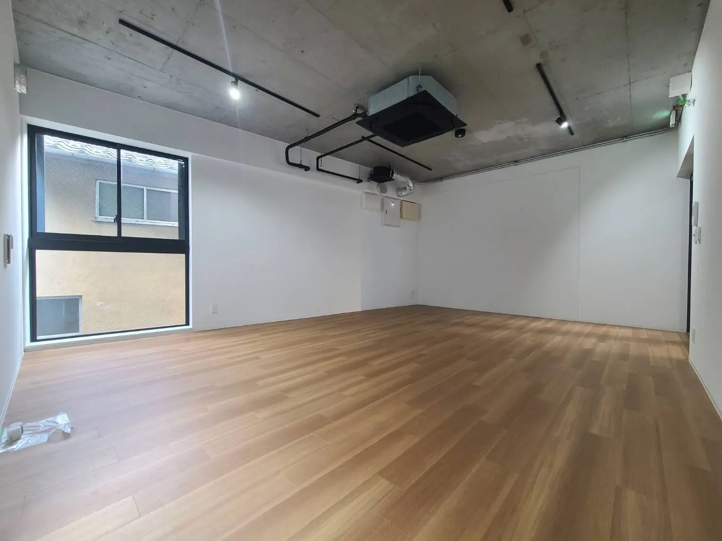 無垢材フローリングのモダンな空間、大きな窓とコンクリートの天井が特徴的なオフィスや店舗に最適なインテリア