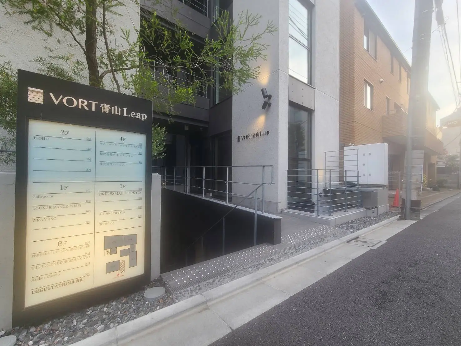 都会的なデザインのオフィスビルVORT青山、案内板と黒い外観、明るい外灯