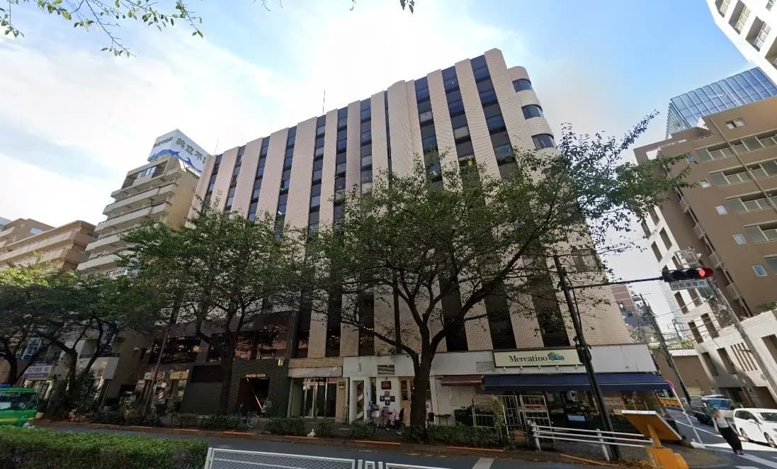 ビルと商店が並ぶ都会の景色、歩道には緑の木々がある街並み