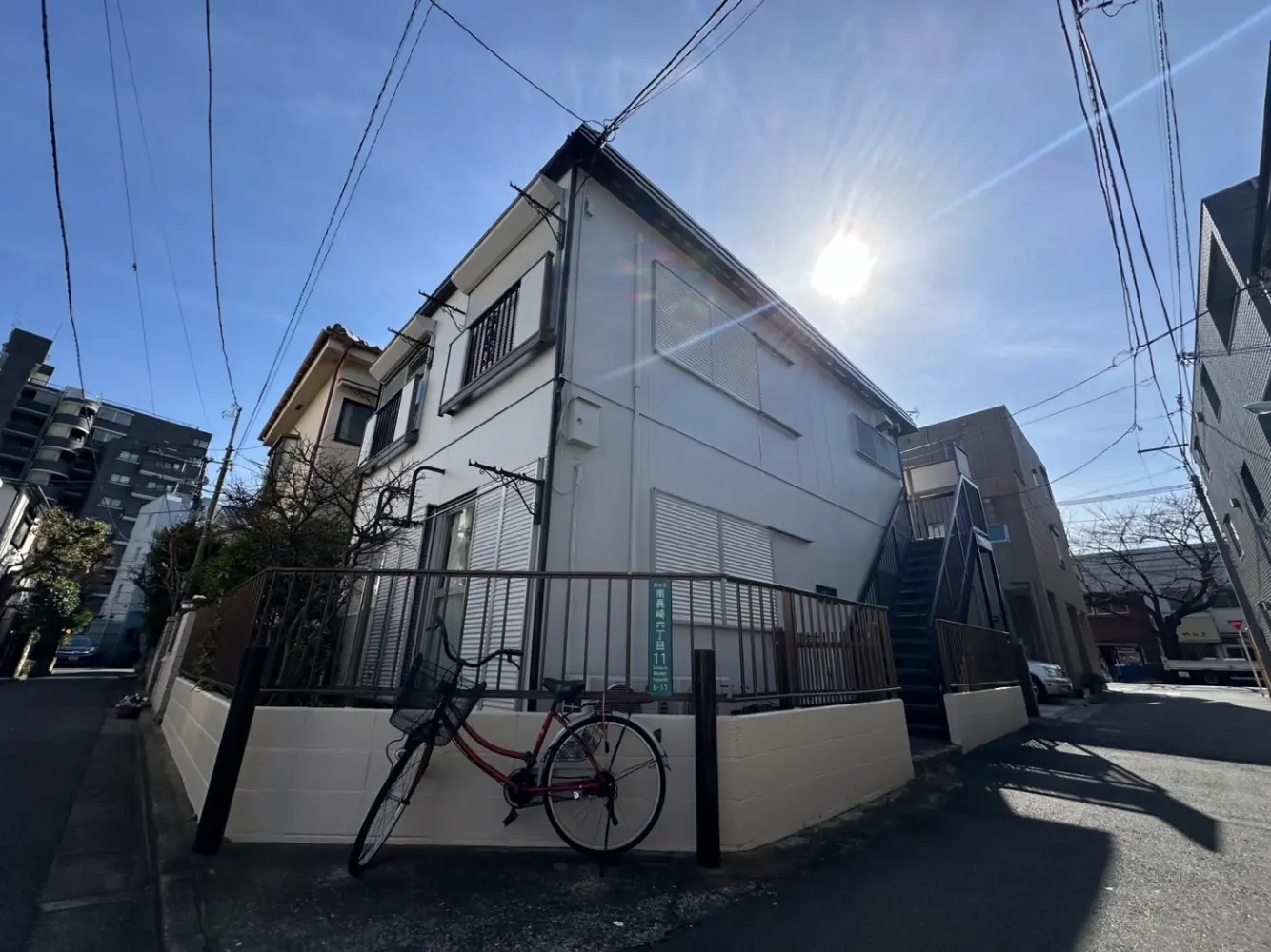 都市の住宅街の風景、白い壁の家、前庭に自転車、青空と太陽の光