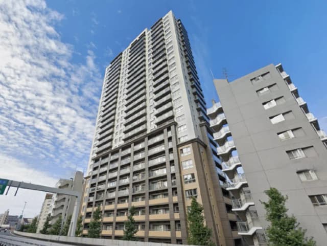 - 青空の下にそびえる高層マンション、近隣の建物と共に都会的な風景を形成する景観