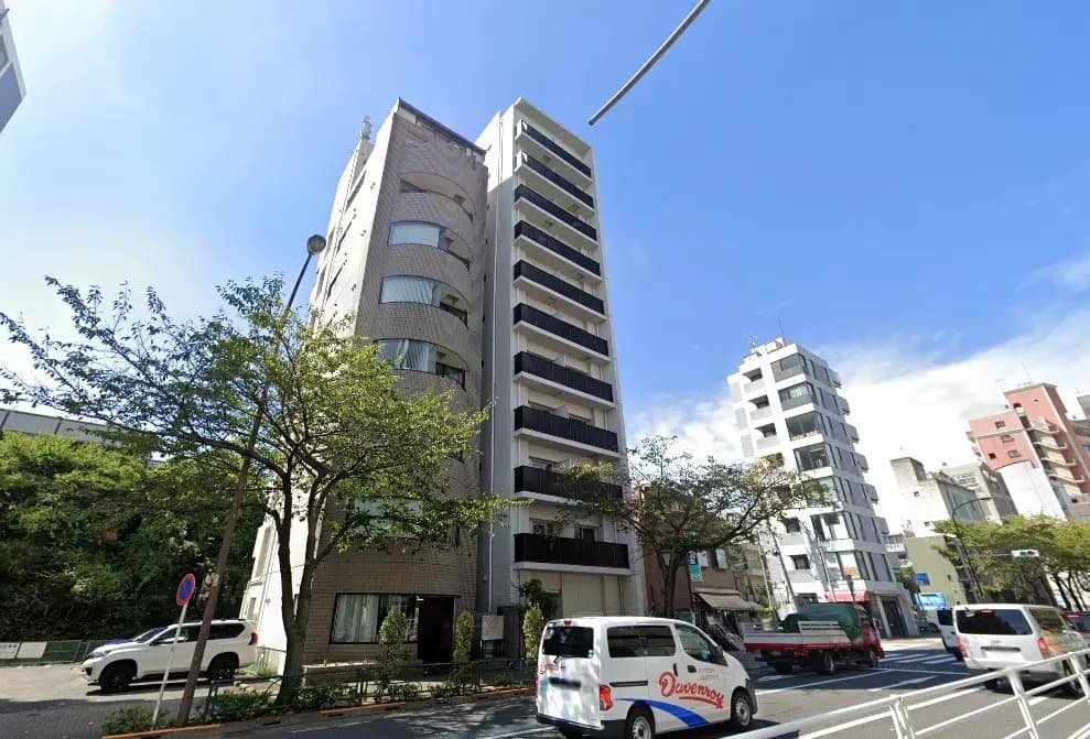 現代的な外観の高層マンション、青空と街路樹がある都市風景