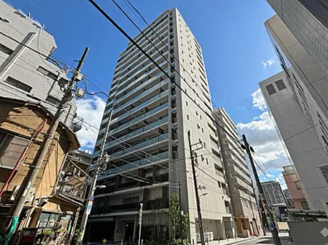 - 近代的な高層マンションと周辺の街並み、晴れた青空と電線が見える都市景観