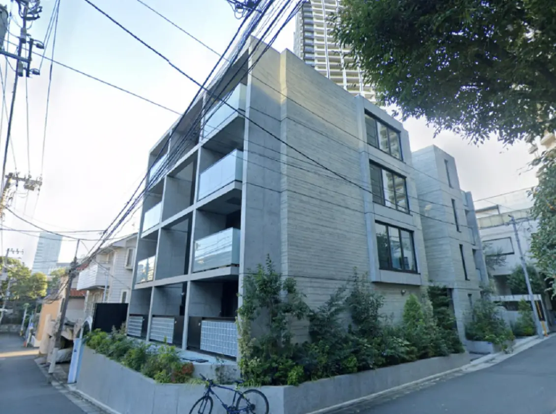 - コンクリート造のモダンなアパートメントビル、バルコニー付きで緑豊かな植栽が周囲にある街並みの風景