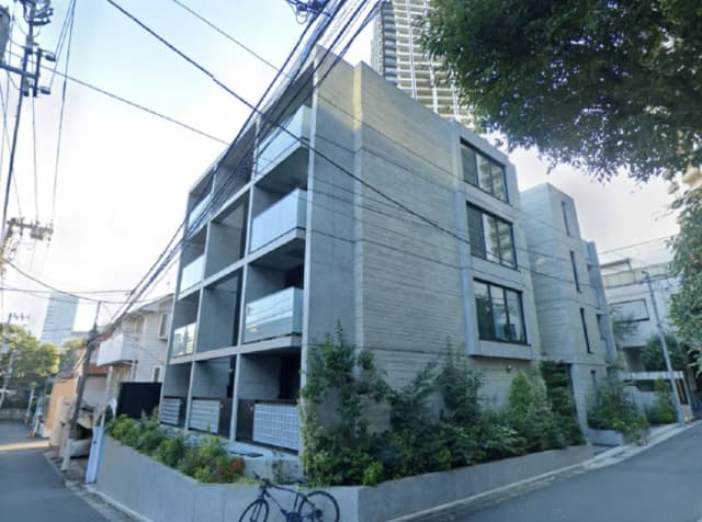 - コンクリート造のモダンなアパートメントビル、バルコニー付きで緑豊かな植栽が周囲にある街並みの風景