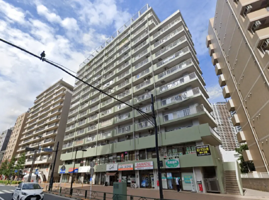 - 近代的な街並みに建つ高層マンション、1階には店舗や飲食店が並ぶ商業エリアの風景