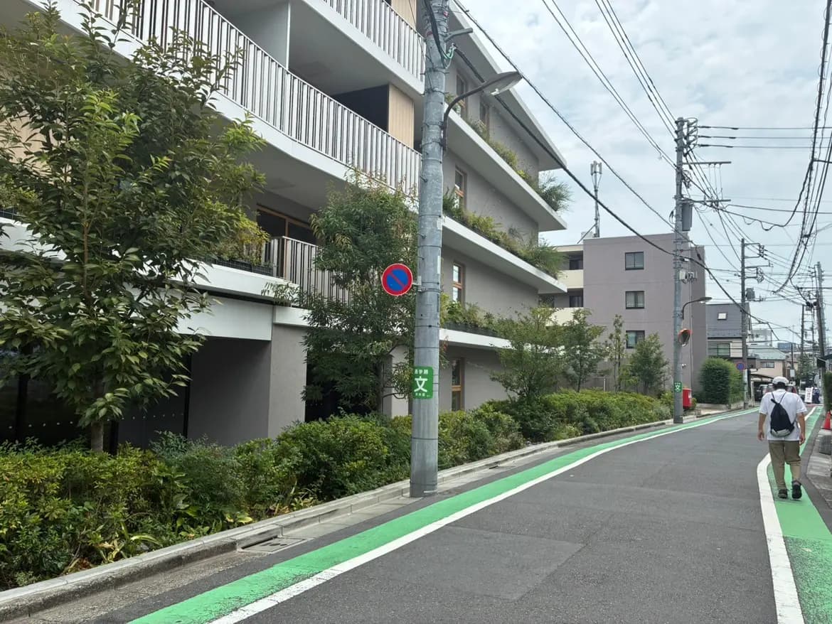 - 緑豊かな街路沿いの住宅、バルコニーのあるモダンな建物と歩道、電線が張り巡らされた風景