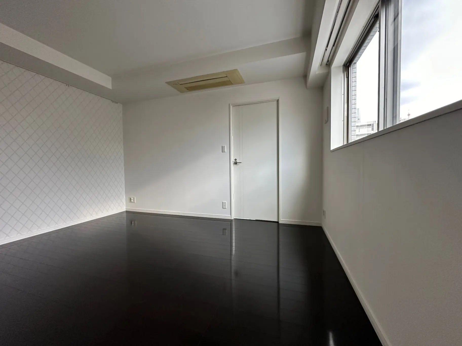 シンプルでモダンなデザインの空の部屋、ダークブラウンのフローリング、大きな掃き出し窓から自然光が差し込むインテリア