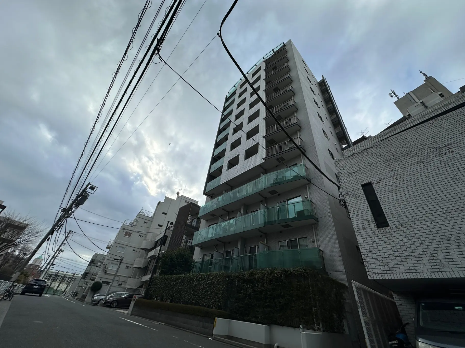 都市の街並み、近代的なマンションと電線、曇り空の下での建築風景