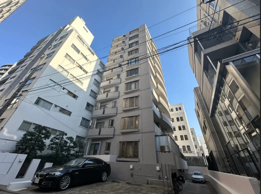 都心の狭い路地に建つ近代的なマンションと駐車された高級車