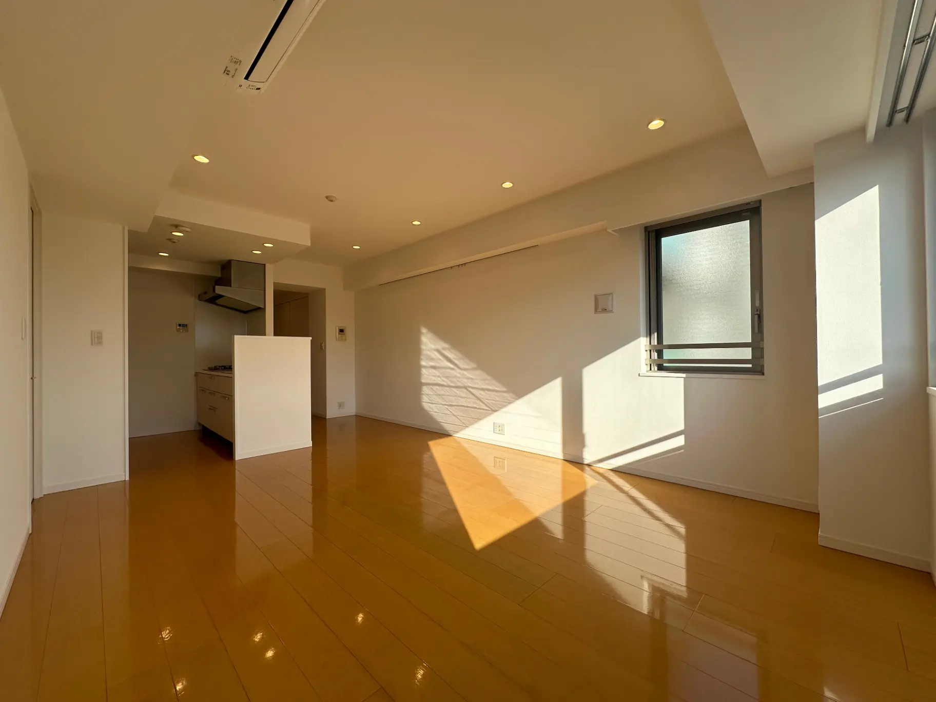 日当たりの良い広々としたリビングルーム、木製フローリング、キッチン付きのモダンなインテリア