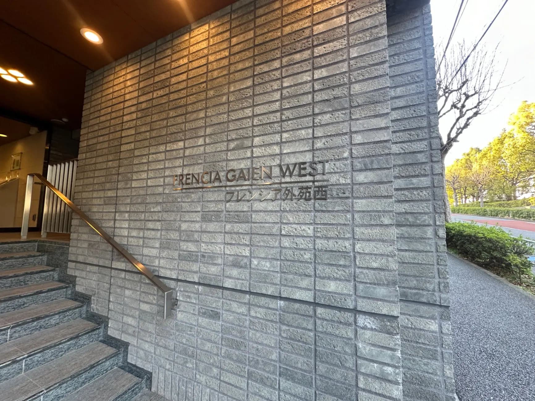 建物の外壁に刻まれた「FRENCIA GAIEN WEST」の文字、石造りの階段と手すりが見えるエントリーウェイ