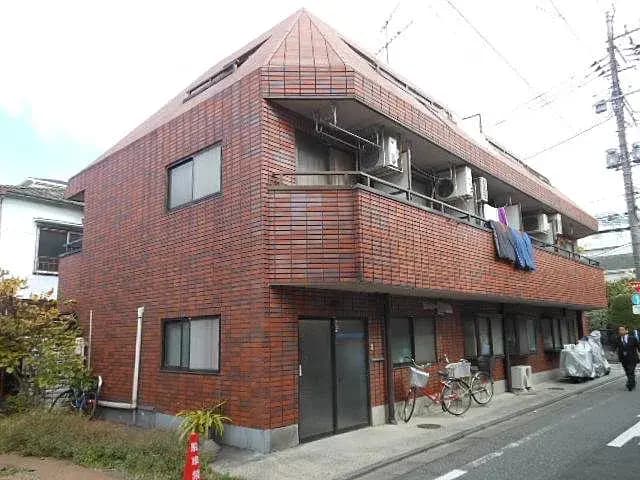 - レンガ造りの外観のアパートメントビル、バルコニーに洗濯物が干されている様子と、周囲に並ぶ自転車が見える街角の風景