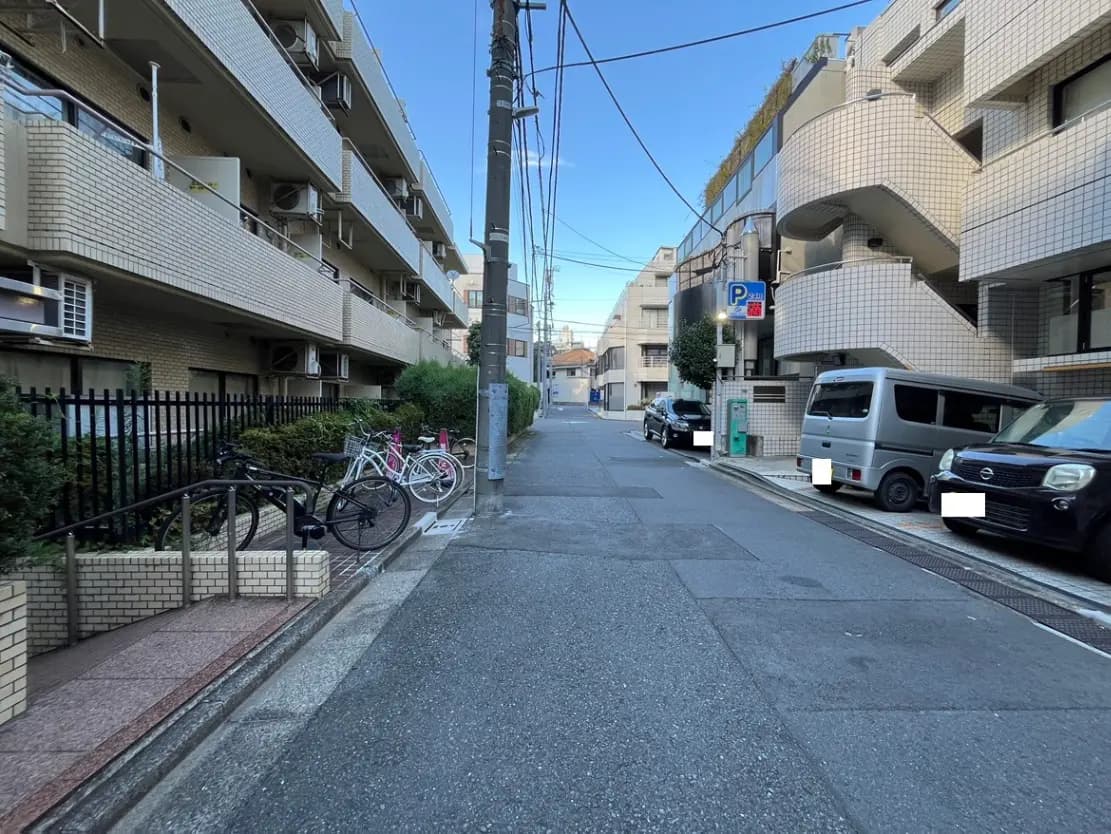 - 住宅街の風景、レンガ造りのアパート、並ぶ自転車と駐車された車、静かな通りの様子