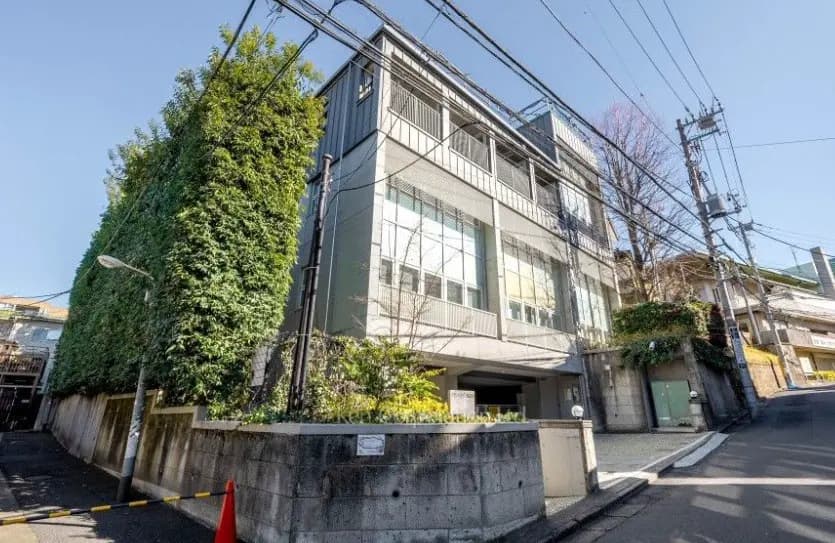 - 緑豊かな外壁が特徴的なモダンな建物、周囲に電柱と道路がある街並みの風景