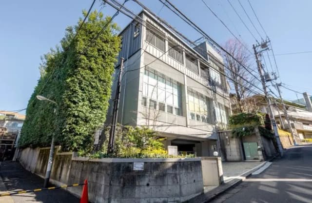 - 緑豊かな外壁が特徴的なモダンな建物、周囲に電柱と道路がある街並みの風景