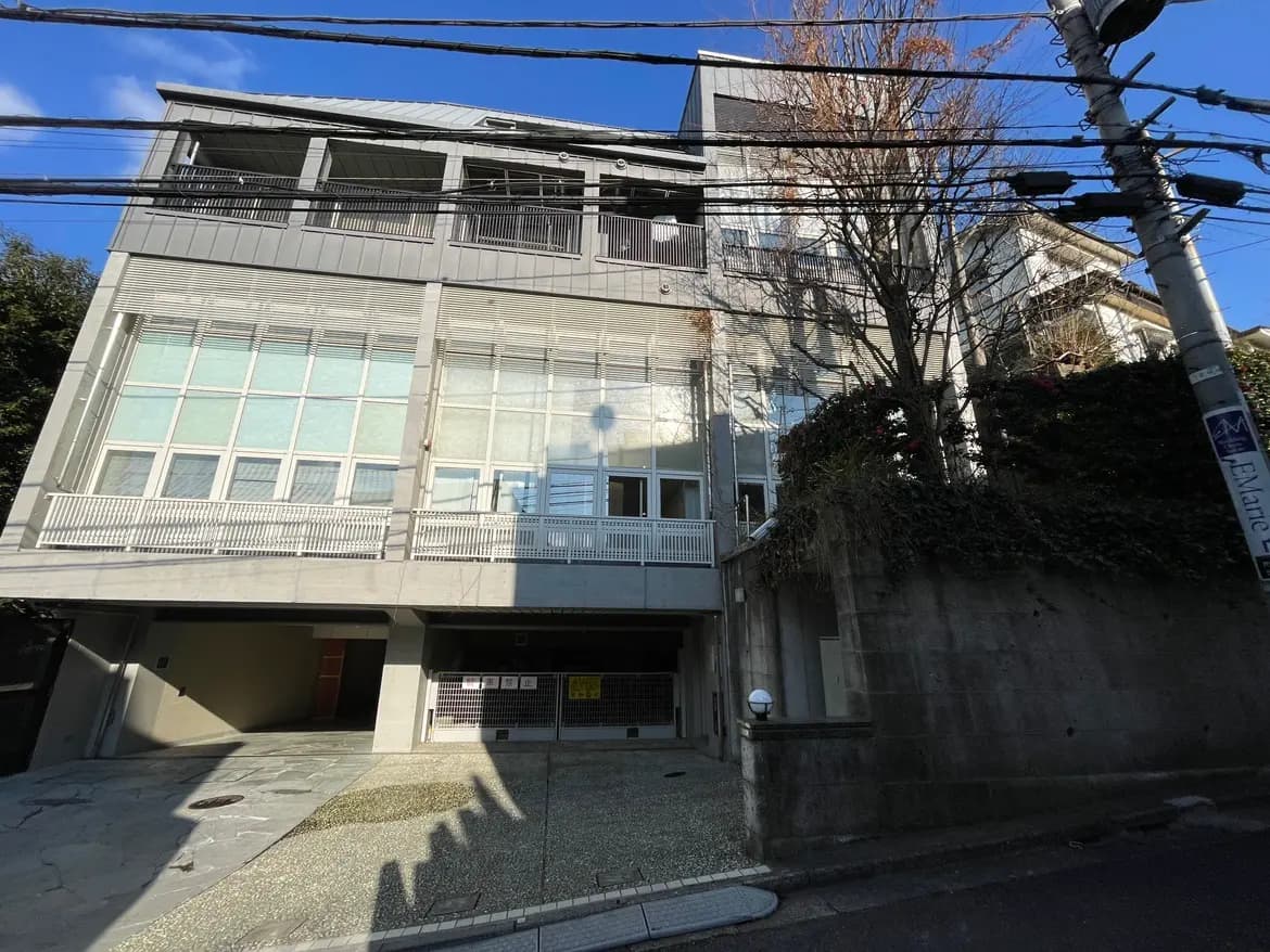 日差しが差し込む現代的な外観の建物、大きな窓とバルコニーが特徴的なアパート