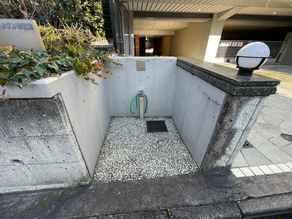 建物の入口付近にあるコンクリートと砂利の配管設備、植物が添えられたアーバンデザイン