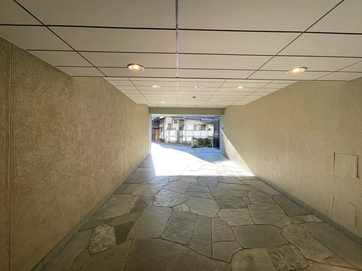 石畳の敷かれたモダンな屋外通路、天井に明るい照明がついた快適なアプローチ 경로