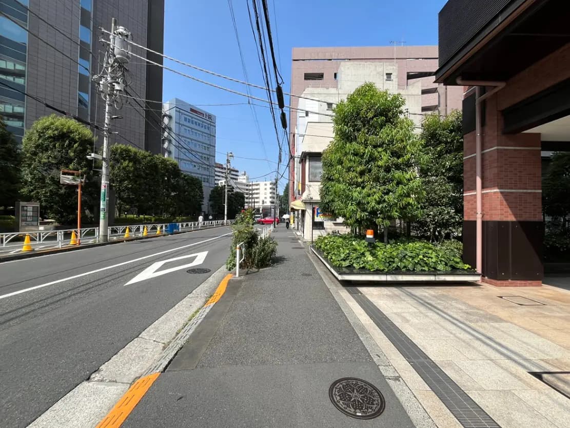 - 都市の街並み、ビルが立ち並ぶ通りと緑の木々、晴れた青空の風景