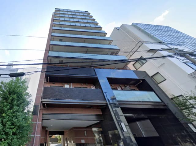 - 現代的なデザインの高層マンション、ガラスのバルコニーが特徴で周囲に高いビルが立ち並ぶ様子