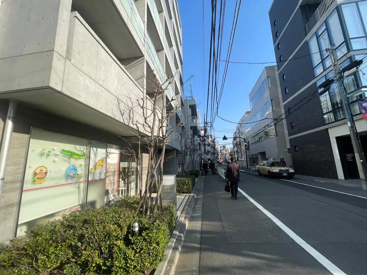都市の街角、歩行者とタクシーが見える晴れた日の風景