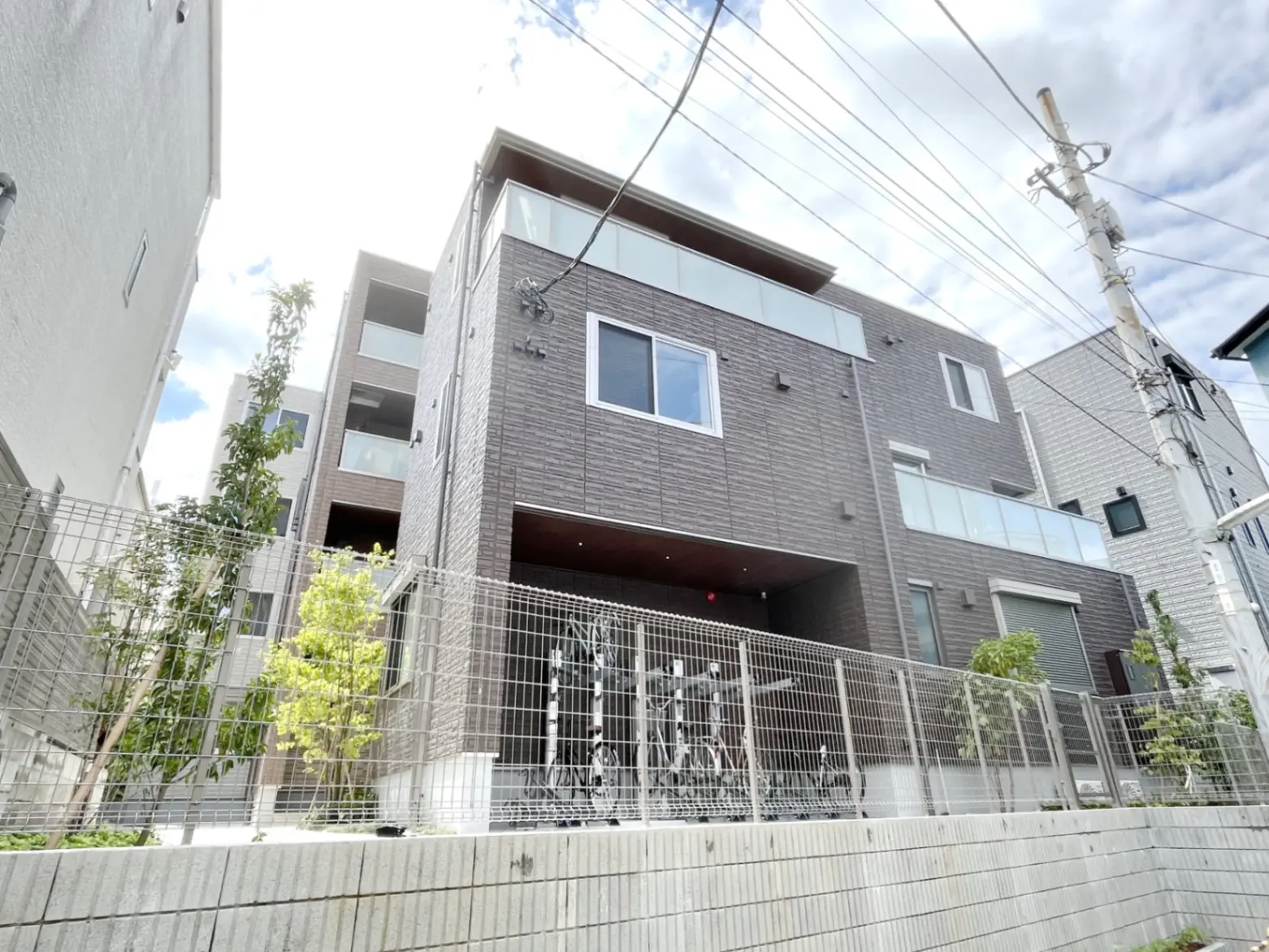 - モダンな外観の三階建て住宅、木材風のサイディング、テラスと庭に囲まれたデザイン