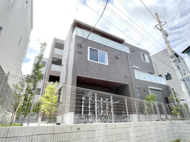 - モダンな外観の三階建て住宅、木材風のサイディング、テラスと庭に囲まれたデザイン