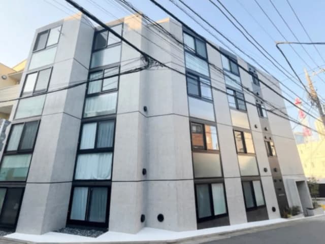 - 現代的なデザインのマンション外観、ガラス窓とコンクリートのファサード、街中の電線が交差する風景