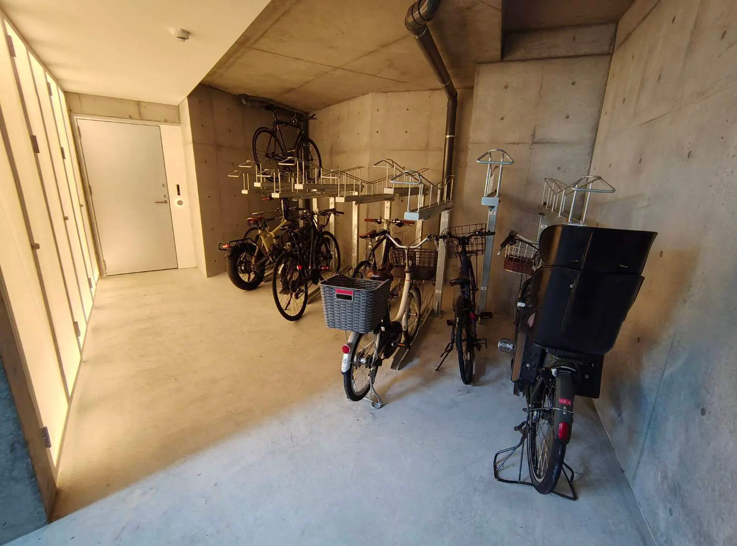- 現代的なデザインの自転車置き場、コンクリートの壁と床、複数の自転車が整然と並ぶスペース