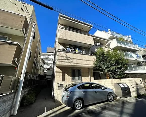 日本の閑静な住宅街にあるベージュの外壁のマンション、青空が広がる晴天の日の都市の風景