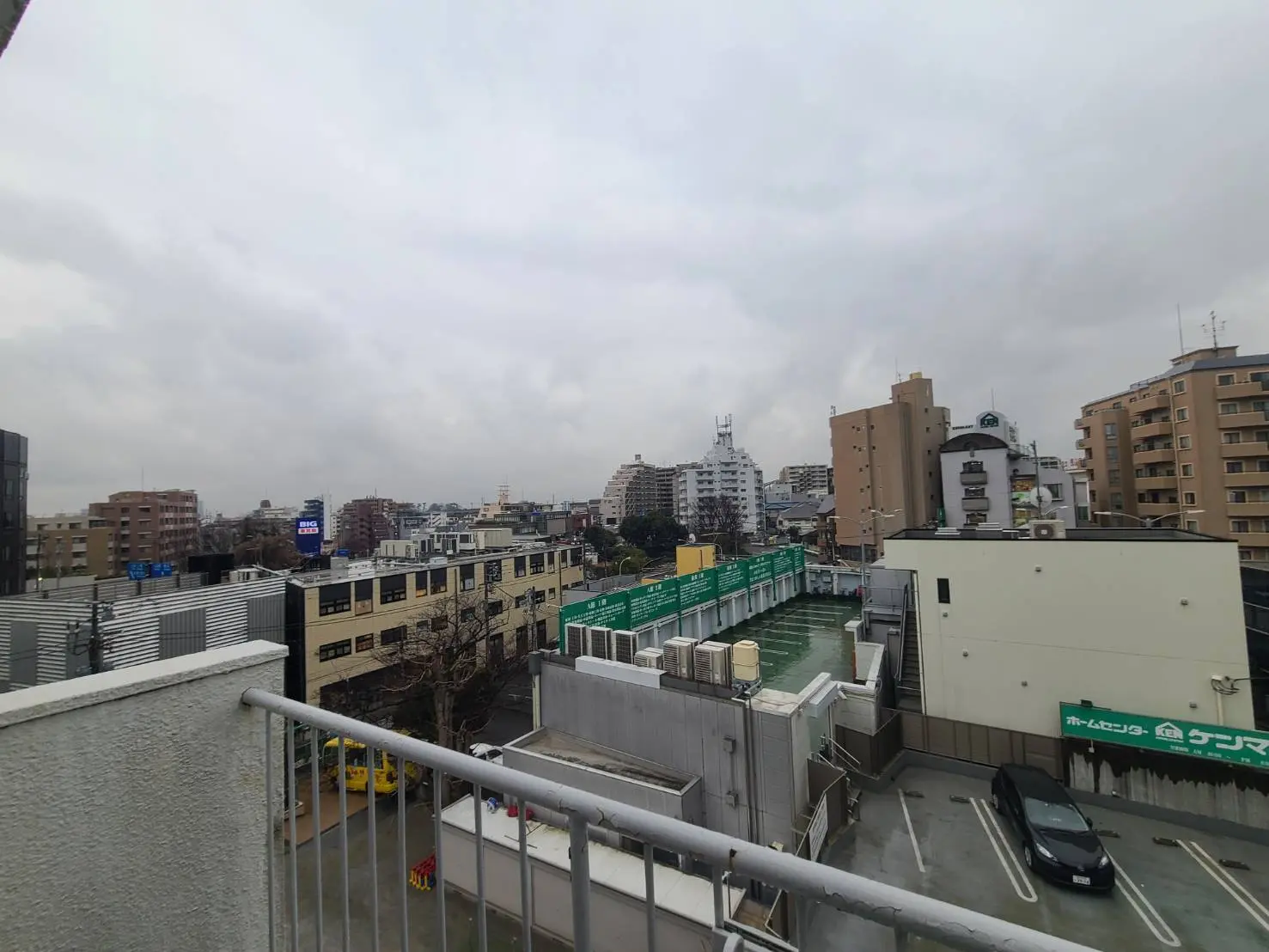 都市の景観、ビルと住宅が混在する地域、駐車場と雲の多い空