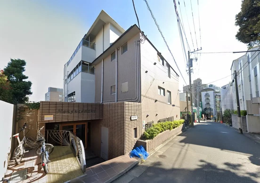 日本の都市部にある現代的な外観のアパートメントビル、狭い道路沿いに立地