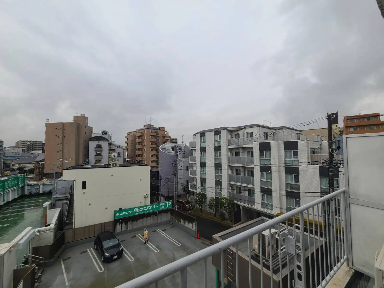 都会の風景、ビルとマンション、車が停まる駐車場、曇り空の日の街並み