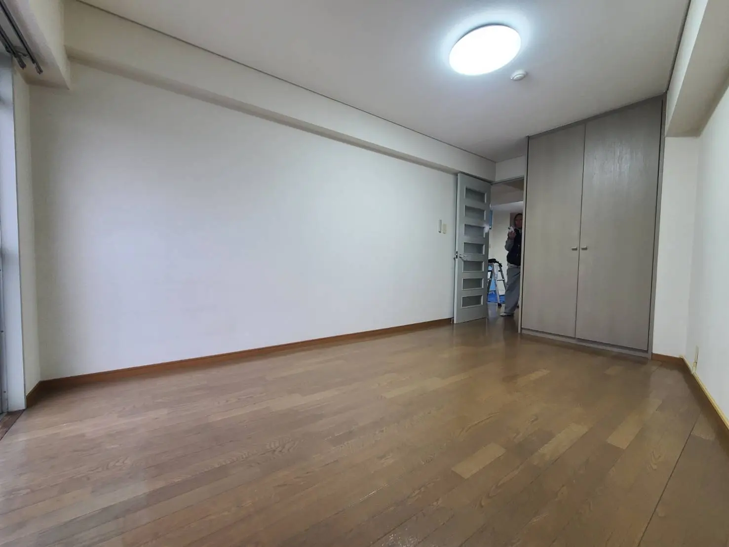 シンプルなデザインの空の部屋、木製のフローリングと白い壁、明るい天井照明付き
