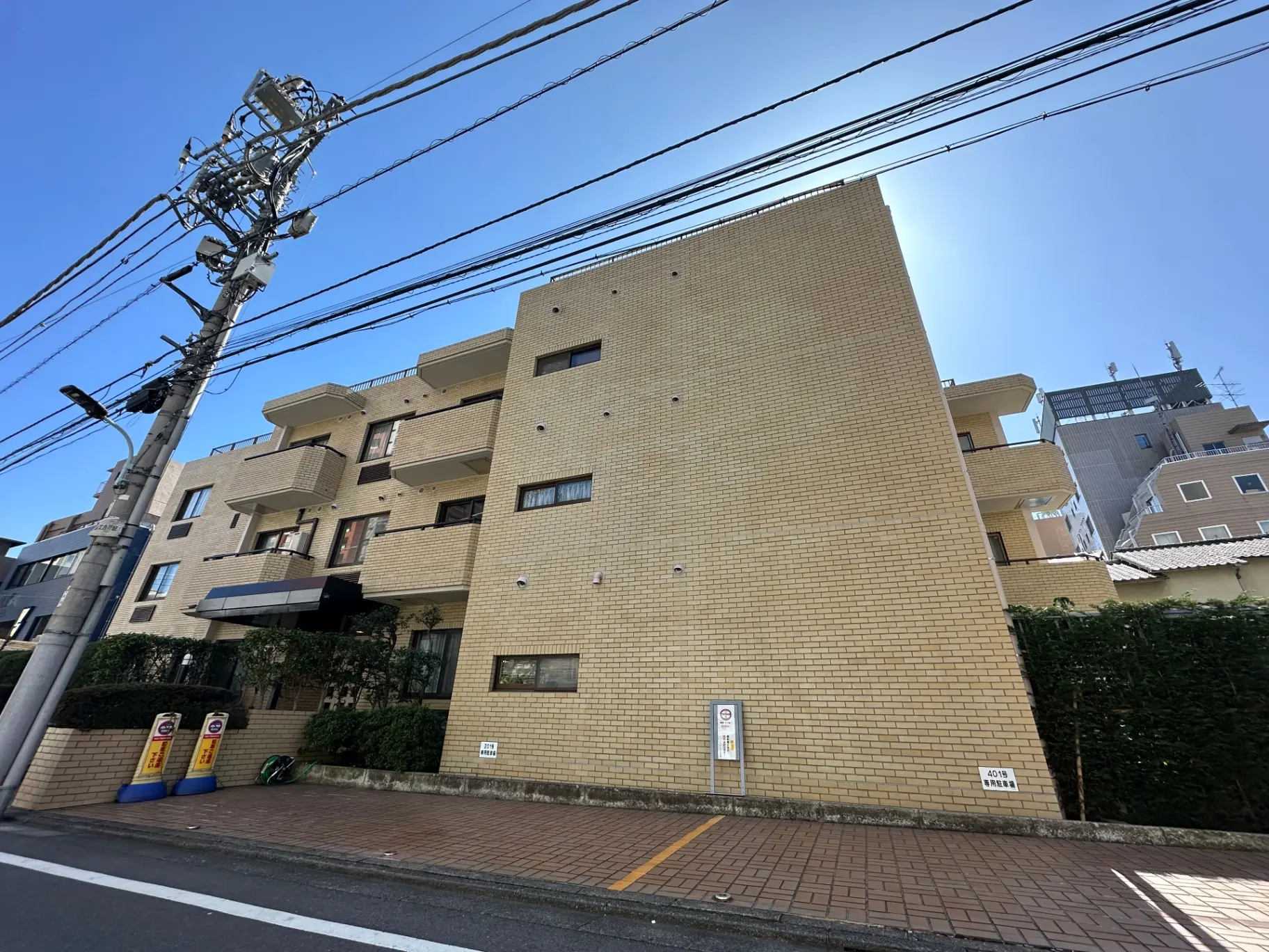都市の電線が張り巡らされた風景、黄色いレンガ造りのアパートメントビル、晴れた日の都市生活の光景
