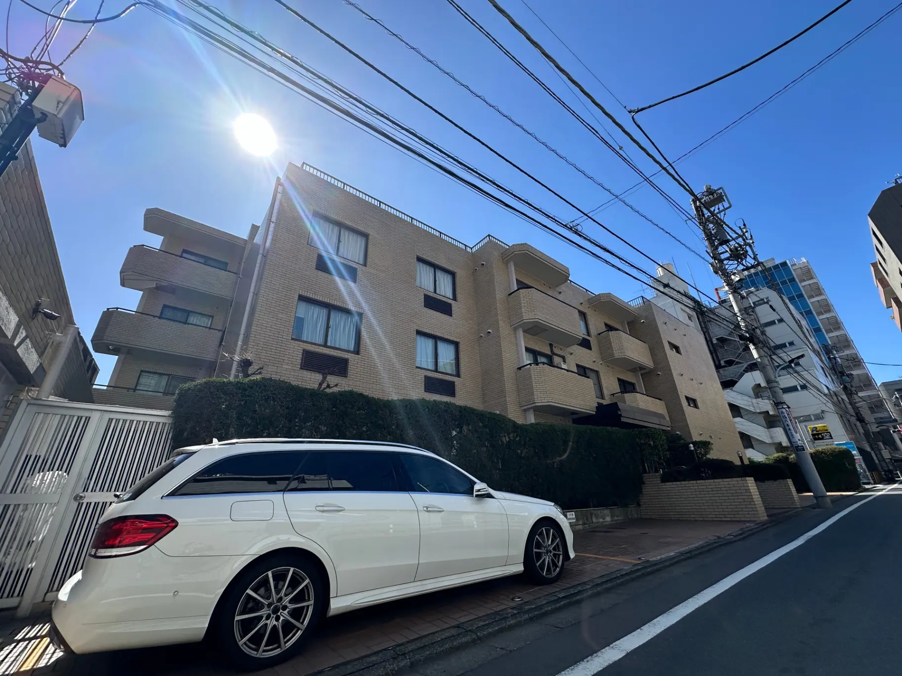 晴れた日の都市風景、ビルと電信柱、駐車している白い高級車
