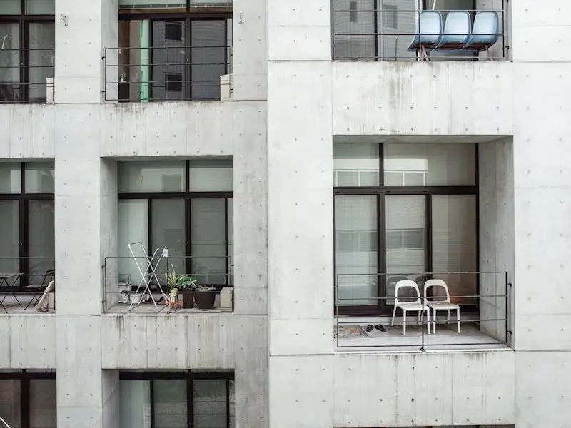 モダンなコンクリート建築のマンションのバルコニー、植物とイスが置かれている