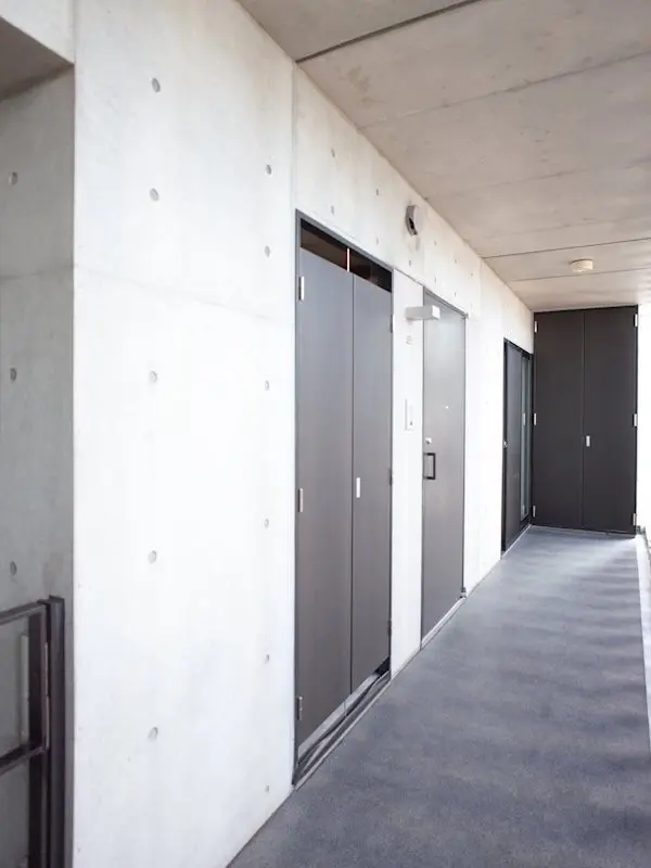 モダンな建物の廊下、コンクリートの壁とカーペットの床、スタイリッシュなエレベーターの扉
