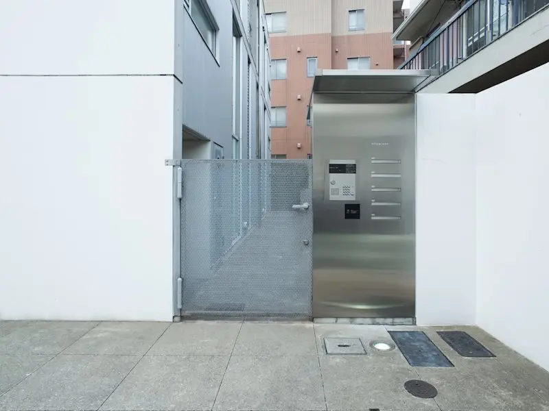 都会的なマンションのエントランス、ステンレス製のインターホンと門扉、建物との隙間に設置