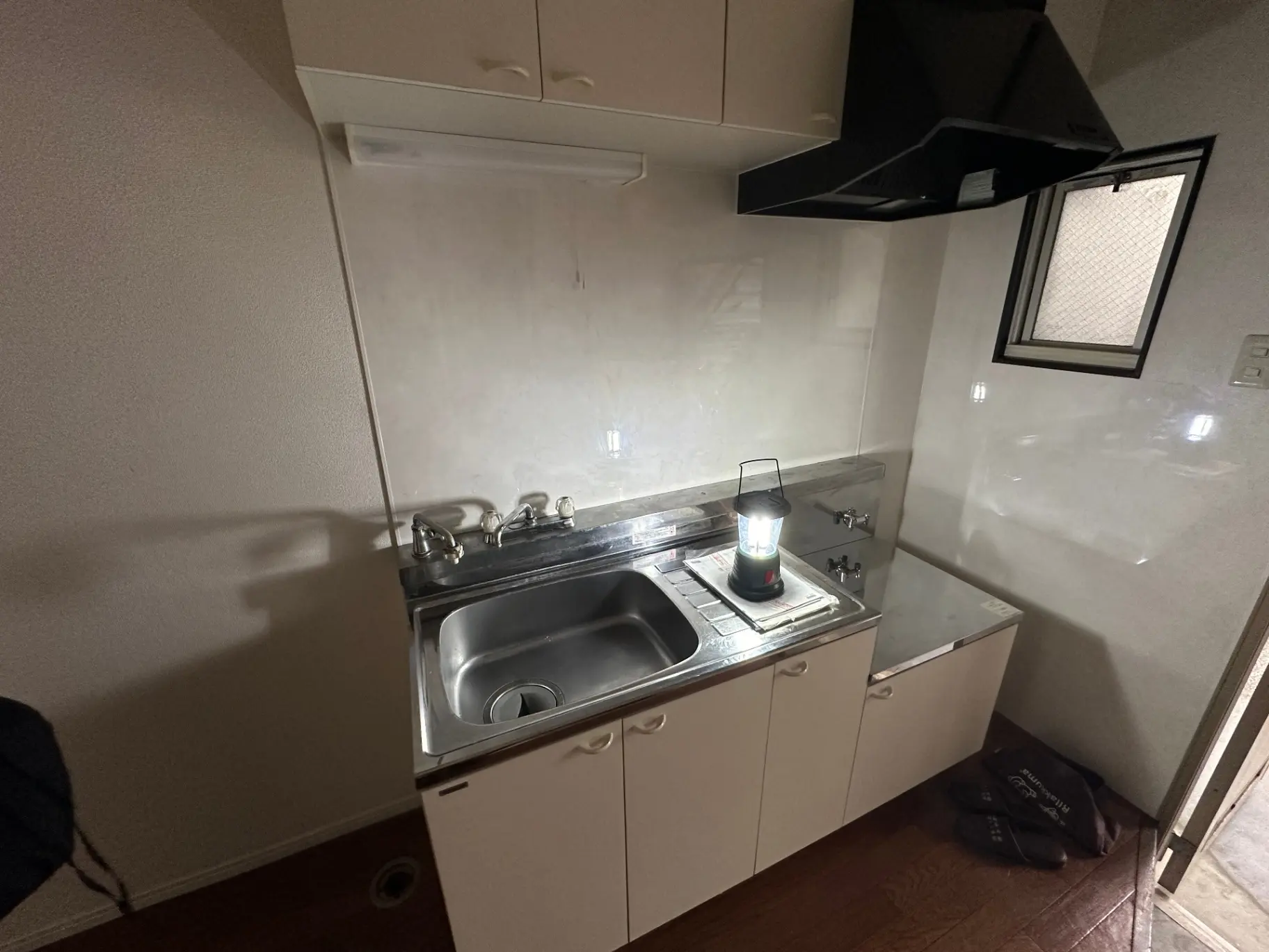 コンパクトなキッチン、シンクと収納キャビネット、小窓からの自然光