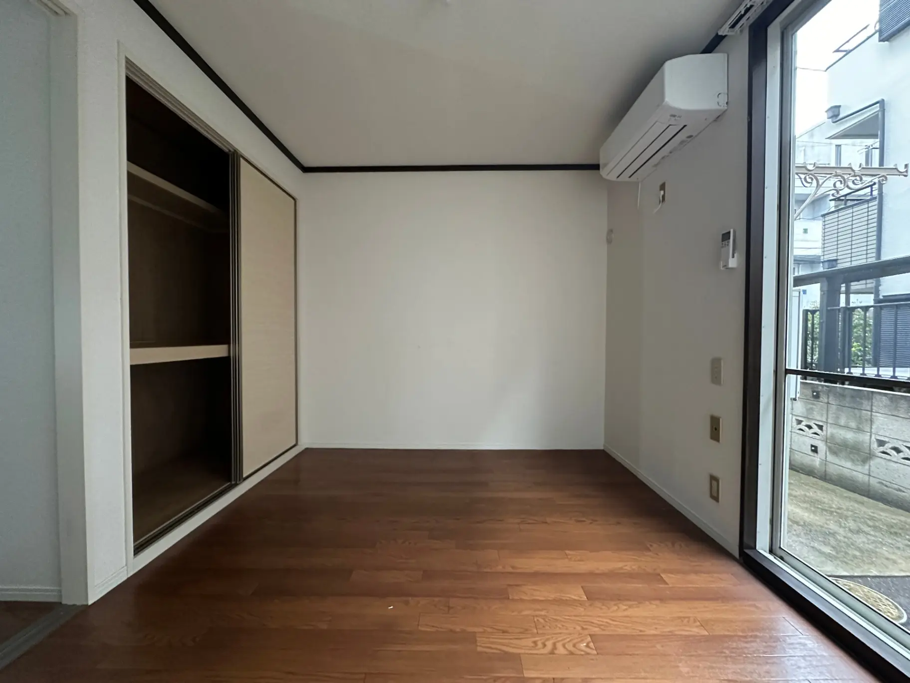 広々とした空き部屋、木製フローリング、白い壁、クローゼット付き、大きな窓からの自然光